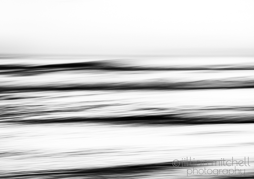 Monochrome abstract ocean wave photograph using intentional camera movement and slow shutter to create blurred horizontal motion and minimalist lines.