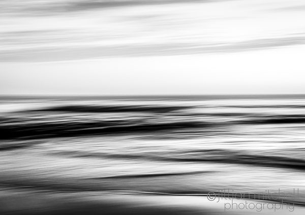 Abstract monochrome seascape with blurred waves and a gentle horizon, created using slow shutter and intentional camera movement.