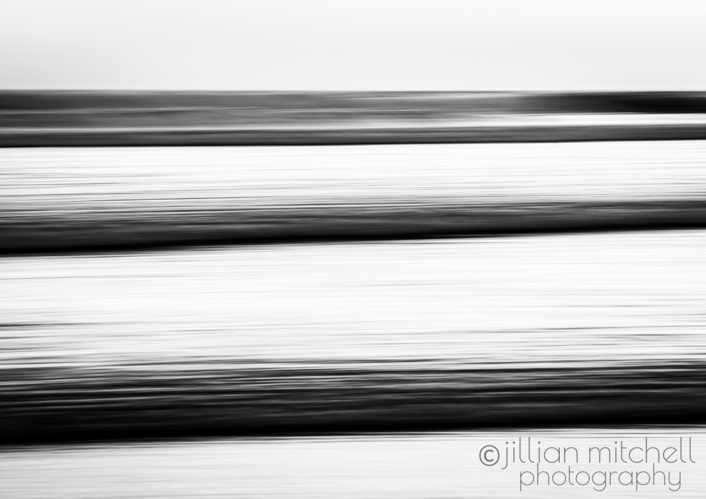 Graphic monochrome ocean abstraction with motion‑blurred horizontal lines produced in‑camera using slow shutter techniques.